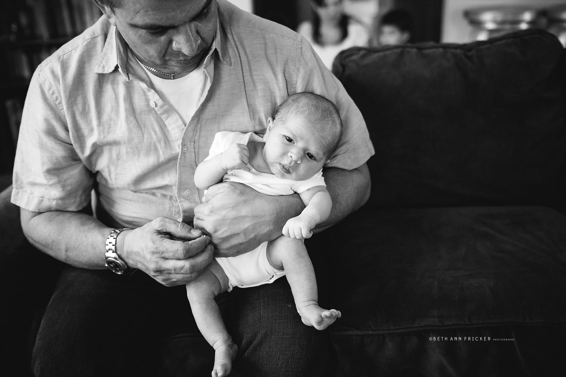dad holding newborn girl in living room couch Boston Baby Photos