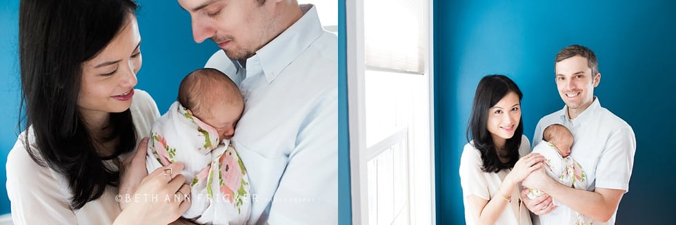 newborn baby with mom and dad in front of blue wall boston newborn photographer