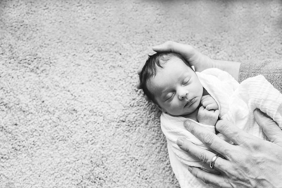 newborn baby girl in parent's hands Boston Newborn PHotographer