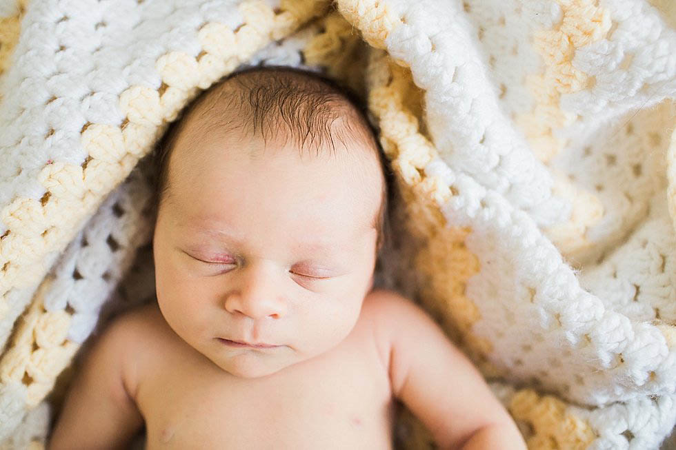 Newborn baby in parents' baby blankets Newton Newborn Photographer