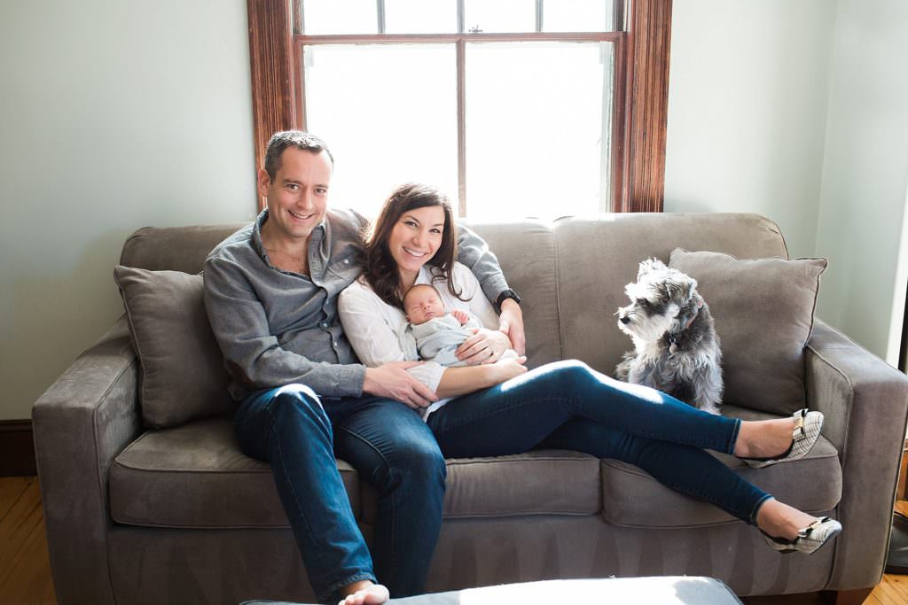 Dog looking on as Mom and dad holding newborn baby daughter Boston Lifestyle Newborn Photos