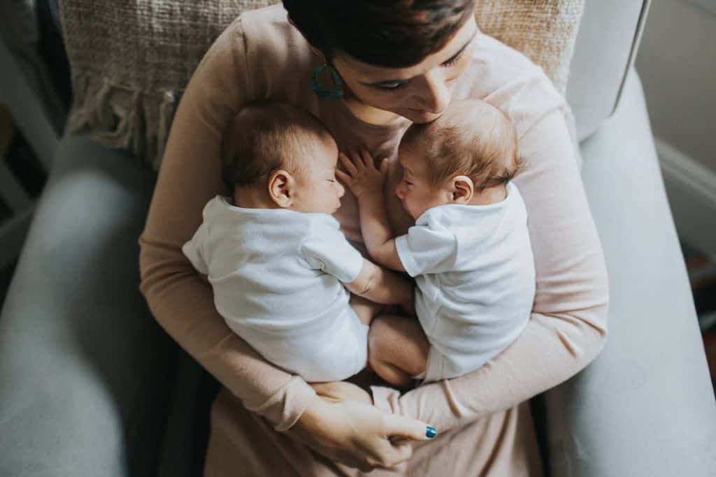 mom with newborn twin boys in nursery boston newborn photos