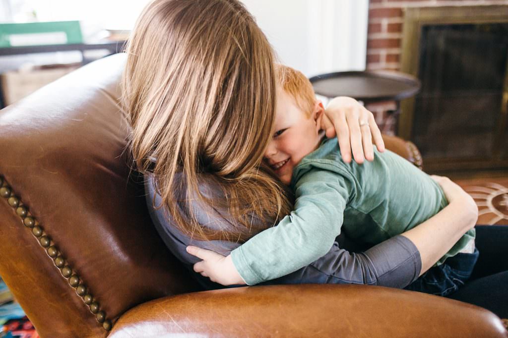 mom snuggling with older son Medford Newborn photographer