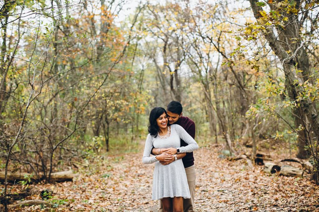 Expecting parents snuggling in forest Boston Maternity photos