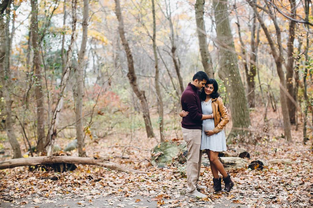 Expecting parents snuggling in forest Boston Maternity photos