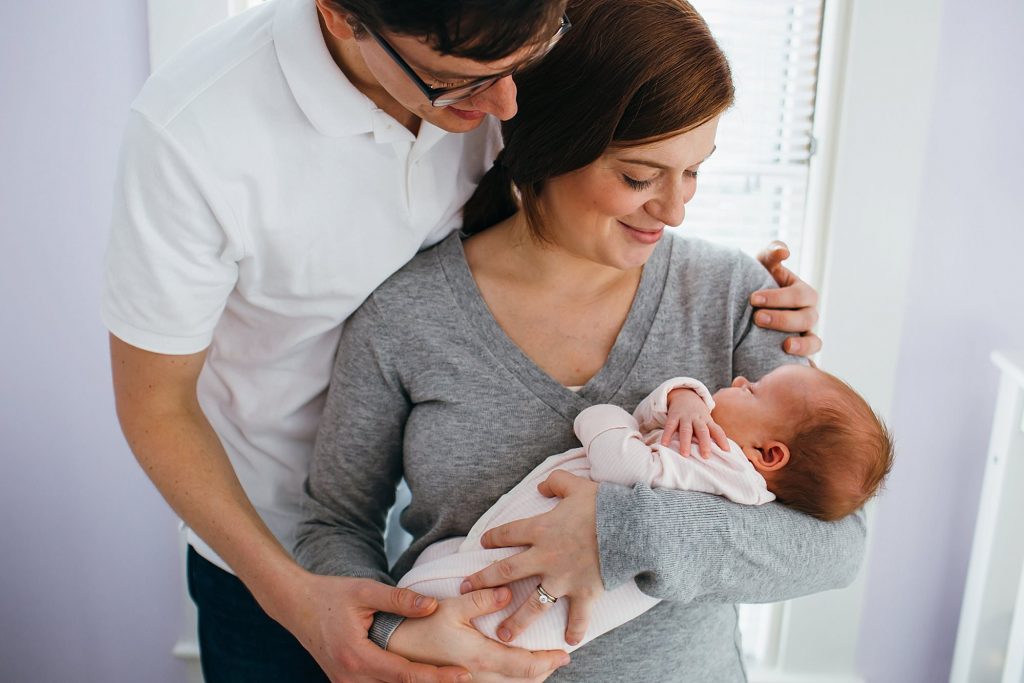mom and dad holding baby in nursery Melrose newborn photography