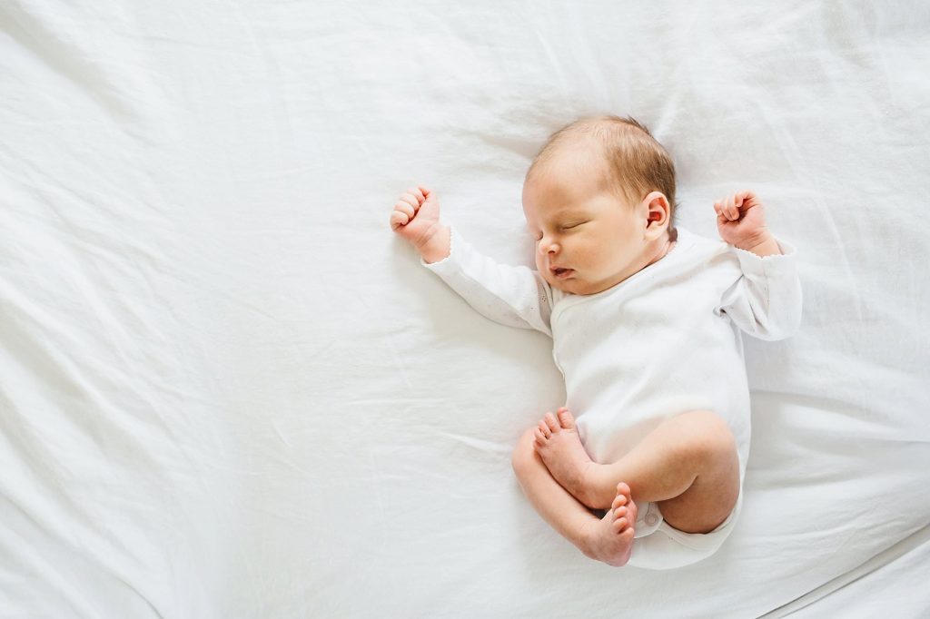 baby stretching on a bed dedham newborn photographer