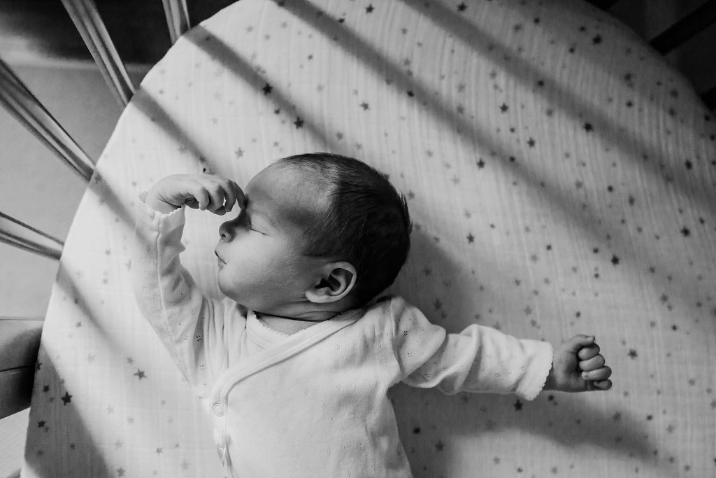 black and white photo of baby in crib dedham newborn photographer