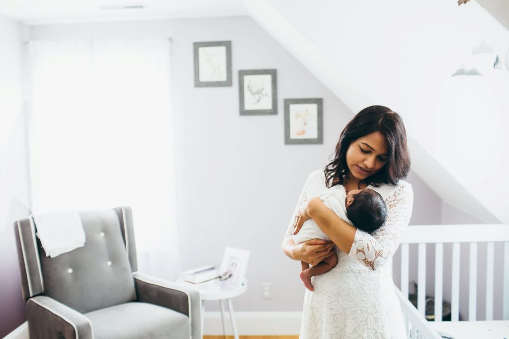 mom holding baby in nursery Arlington Newborn Photographer
