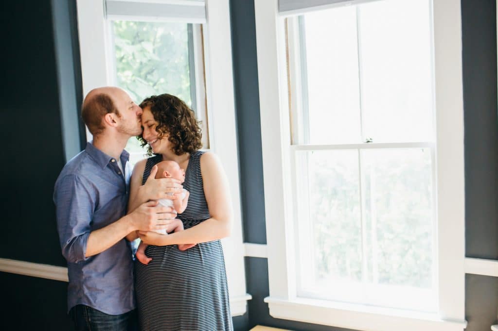 dad kissing mom while holding baby brookline photographer 