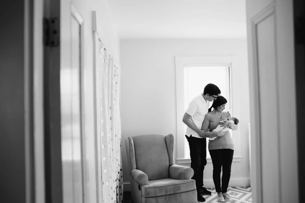 parents with baby in nursery melrose newborn photographer