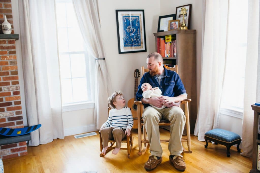 dad holding baby with son in rocking chairs north shore newborn photographer