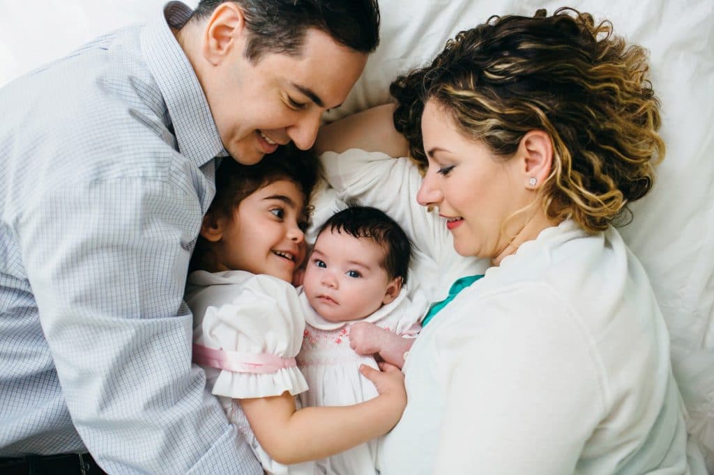 Family snuggling on bed with baby weston newborn photographer