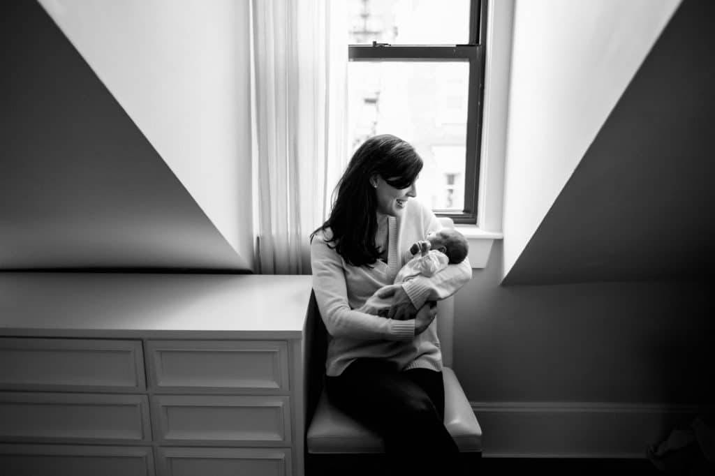 mom holding baby by window Charlestown newborn photographer
