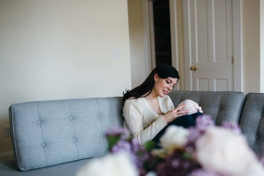 mom sitting on couch with baby Charlestown newborn photographer