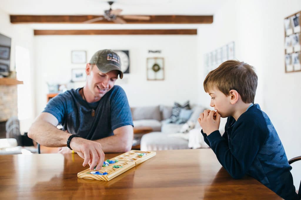 father and son playing a game together at the kitchen table South Shore family photographer