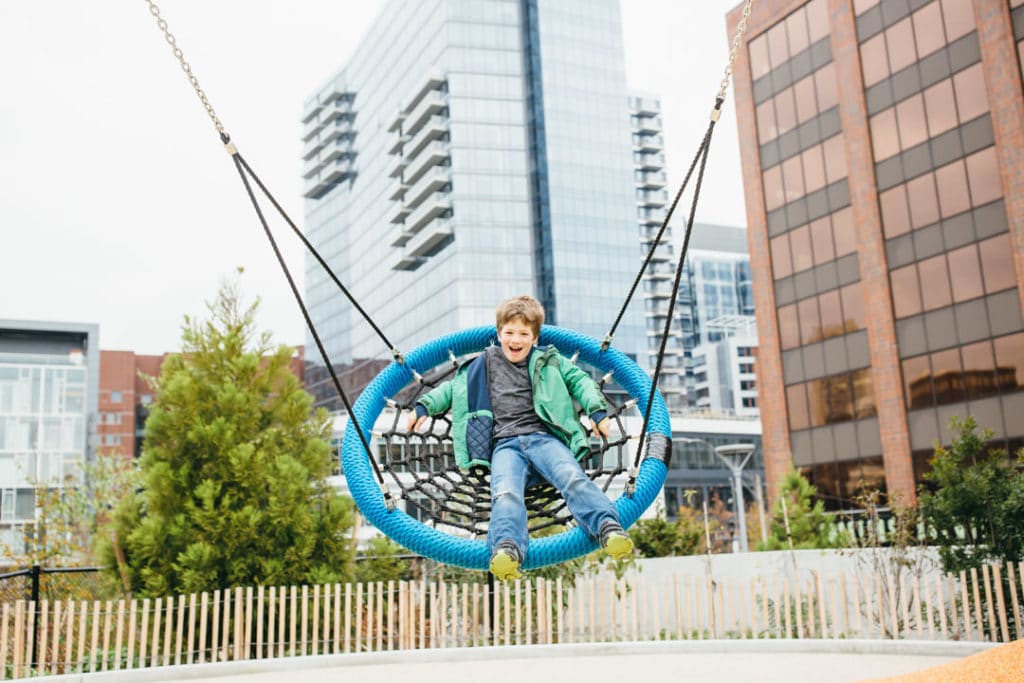 boy swinging on webbed swing at Martin's Playground in Boston