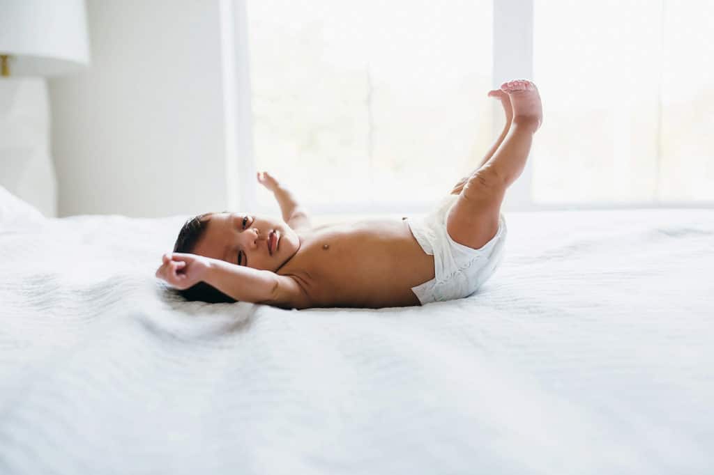 baby stretching on bed Boston newborn photographer