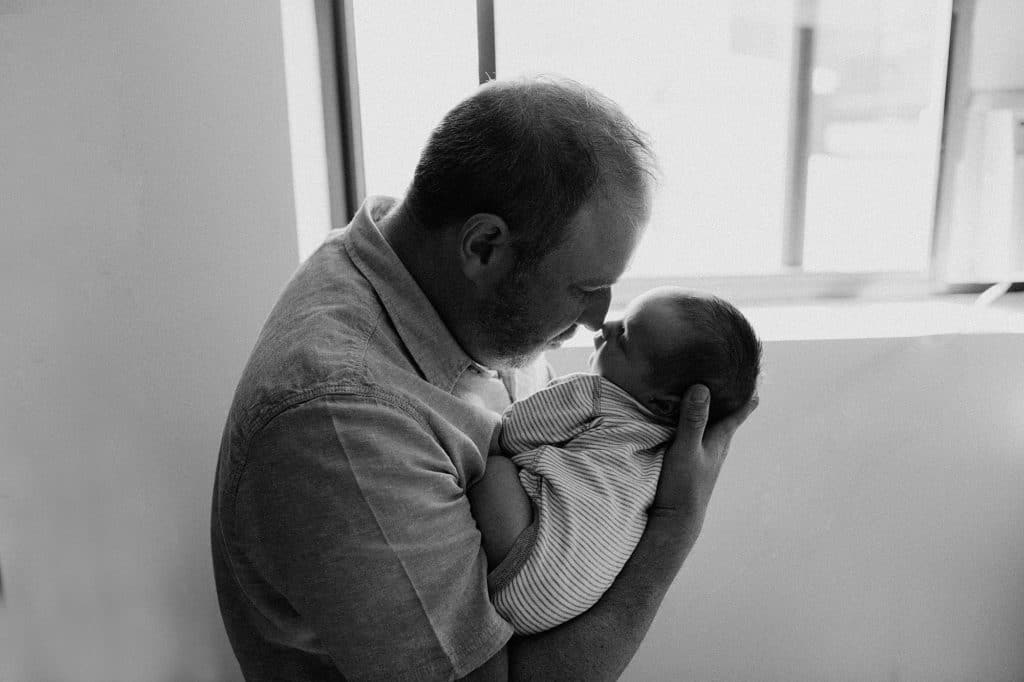 black and white portrait of dad looking at baby lovingly boston newborn photographer