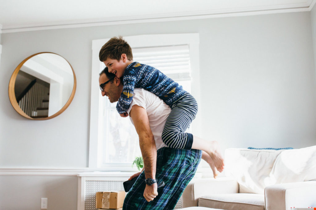 boy getting a back ride from his dad in the living room