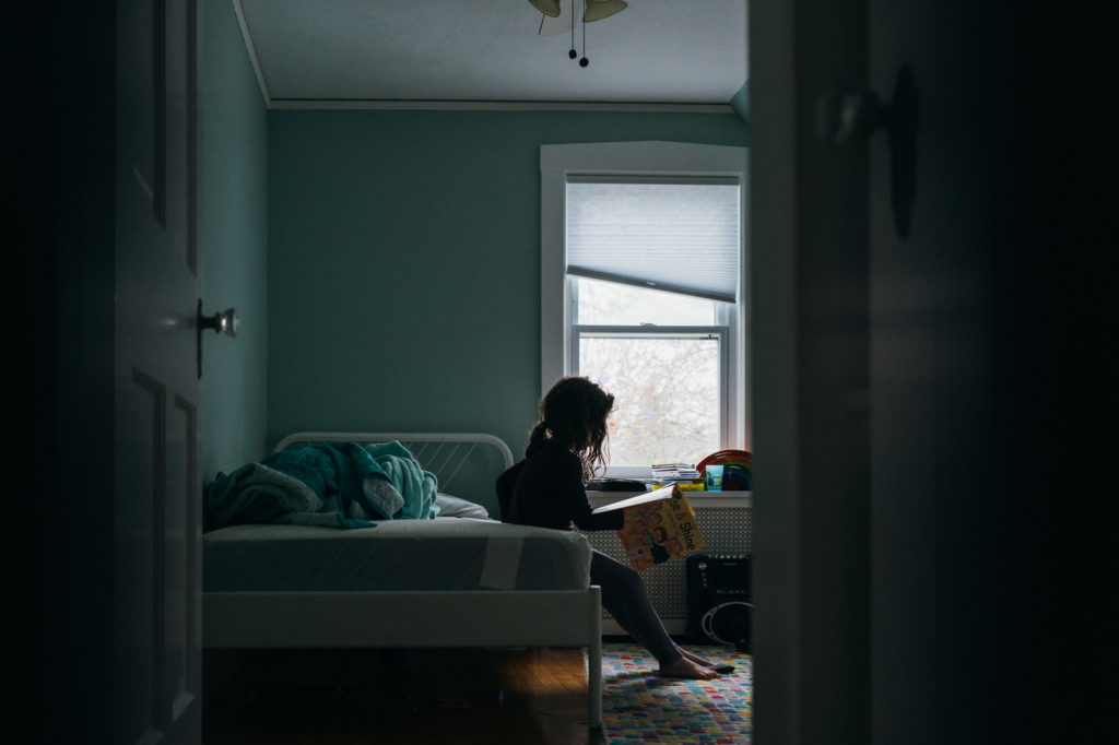 silhouette image of a girl reading a book in her bedroom boston family photography
