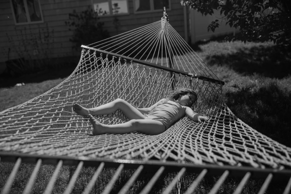black and white image of girl laying in a hammock during the summer in Belmont