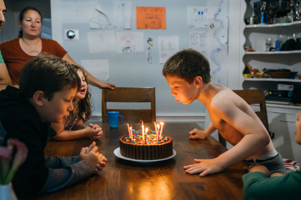 boy blowing out birthday candles on a m&m cake boston family photographer