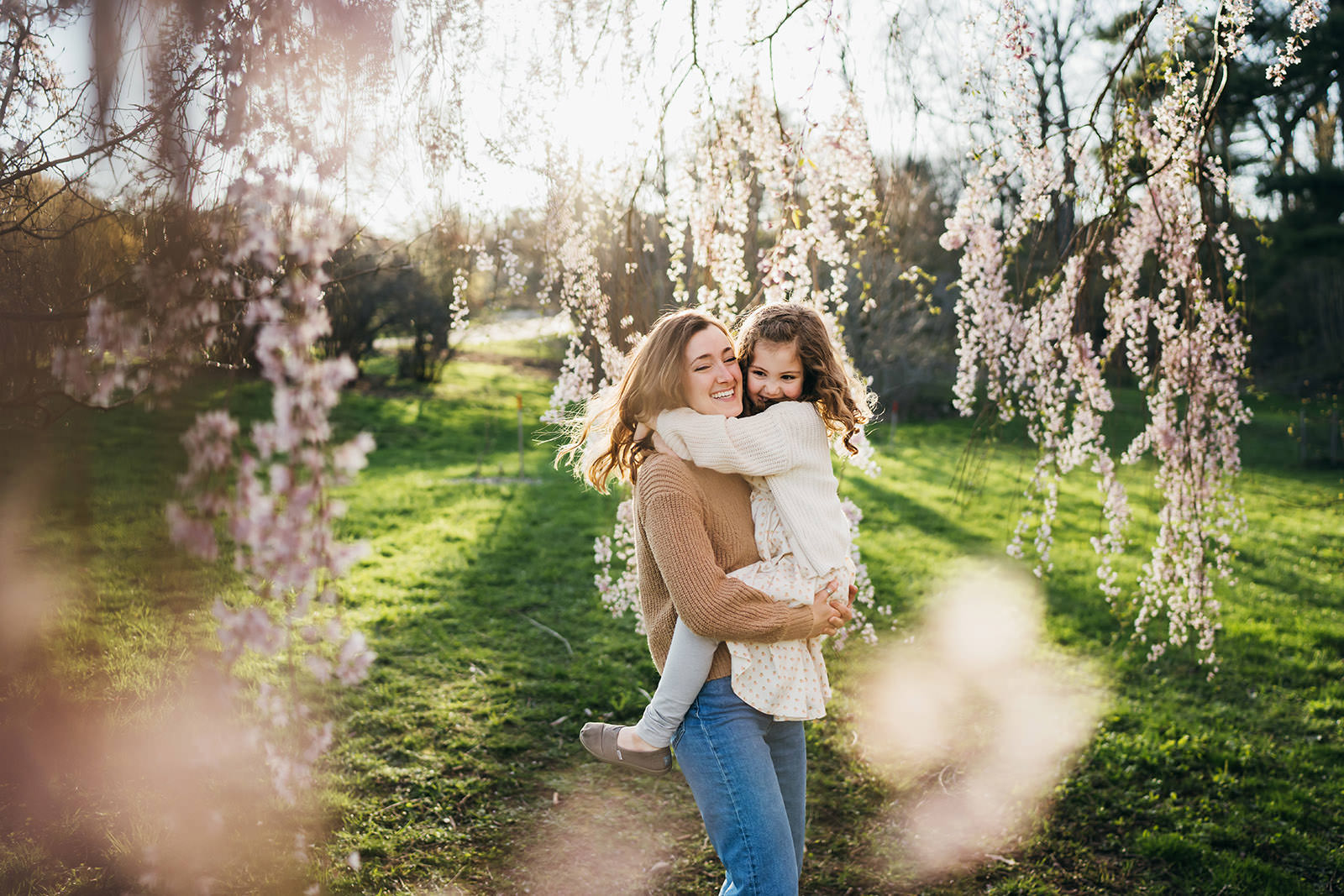 mom and girl playing underneath flower blossoms in the spring